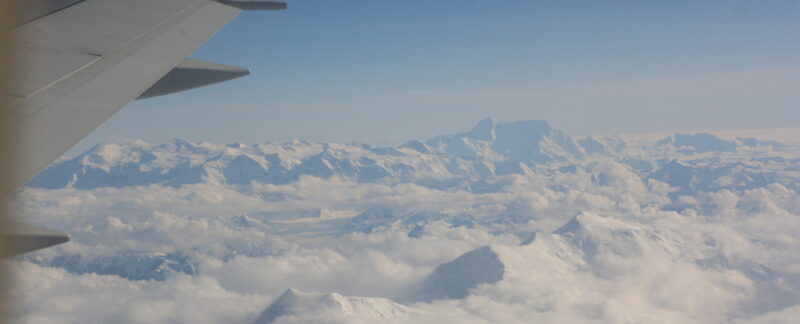 Alaskan mountains seen from airplane above the clouds